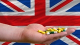 holding pills in hand in front of great britain national flag