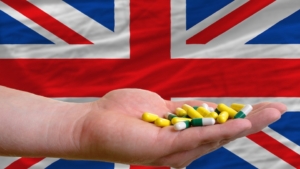 holding pills in hand in front of great britain national flag