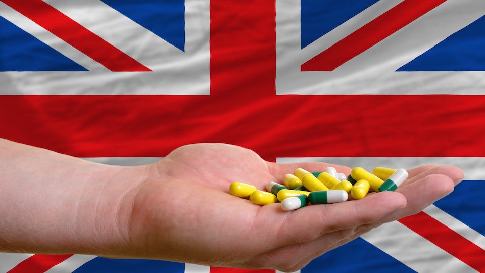 holding pills in hand in front of great britain national flag