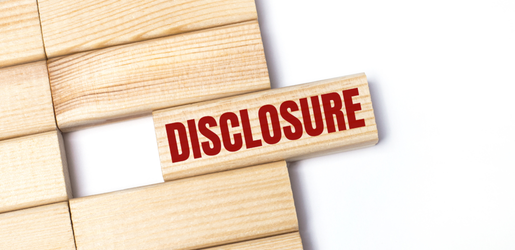 On a light background, wooden blocks with the text DISCLOSURE. Close-up top view.