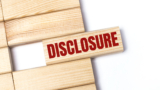 On a light background, wooden blocks with the text DISCLOSURE. Close-up top view.
