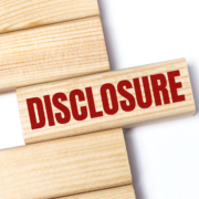 On a light background, wooden blocks with the text DISCLOSURE. Close-up top view.